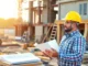 Experienced contractor inspecting construction progress on a busy site with blueprints and safety gear, demonstrating professionalism and expertise.