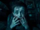 A distressing scene of Harvey sitting in a dark room with shop tools nearby, conveying psychological horror and moral conflict.