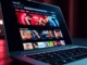 A laptop displaying an adult entertainment website homepage with video thumbnails and colorful banners.